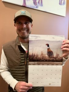 Tanner Cherney of Peak Productions holding the 2020 Pheasants Forever Calendar with his photo used for March.